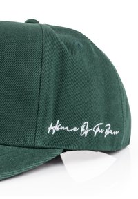 Cappellino da baseball verde con tessuto testurizzato; presenta la scritta ricamata bianca "Home Of The Brave" sul lato.
