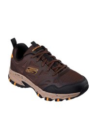 Brown athletic shoes with black and orange accents, mesh upper, reinforced toe, and textured sole featuring multi-directional grip.