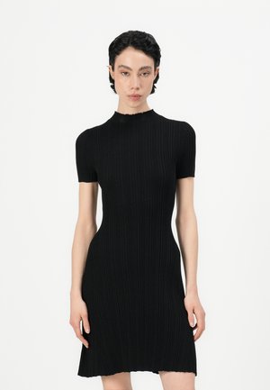 Black ribbed knit dress with short sleeves, high neckline, and a fitted silhouette. Features a flared hem with a raw edge.