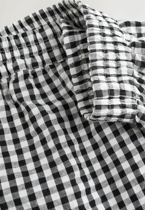 Tissu à carreaux noir et blanc avec une taille élastique décontractée. Le motif présente de petits carrés avec une texture douce.