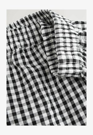 Tissu à carreaux noir et blanc avec une taille élastique décontractée. Le motif présente de petits carrés avec une texture douce.