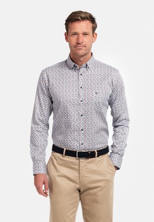 Chemise boutonnée avec une base blanche et un motif géométrique en bleu, orange et rouge. Manches longues, texture lisse, avec un col classique.
