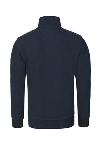 Mörkblå jacka i mjukt tyg med hög krage, ribbade muddar och midjeband. Sömlös baksida utan synliga logotyper eller detaljer.