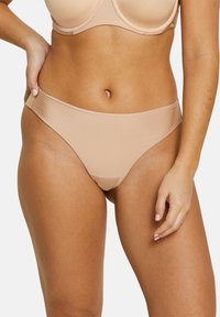Culotte bikini nude en tissu lisse et extensible, avec des ouvertures de jambes dégagées et une taille sans couture, conçue pour le confort et un ajustement élégant.