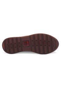 Brown rubber shoe sole with textured surface, featuring rectangular and circular patterns, and a central embossed logo.