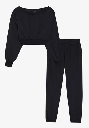 Schwarzes, passendes Loungewear-Set mit einem kurz geschnittenen Langarmtop mit weitem Ausschnitt und hochgeschnallten Hosen mit elastischen Bündchen.