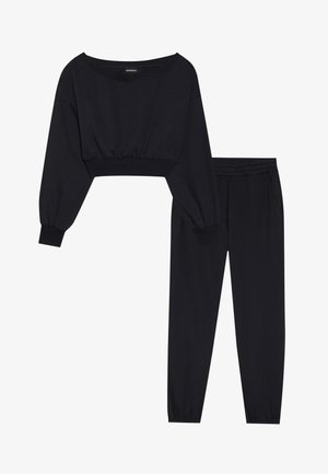 Completo coordinato in nero per il tempo libero, composto da un top corto a maniche lunghe con scollatura ampia e pantaloni a vita alta con polsini elastici.