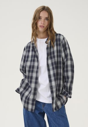 Marineblå og hvidternet flannel skjorte med løs pasform, knaplukning foran og lange ærmer over en hvid T-shirt. Let tekstur og afslappet design.