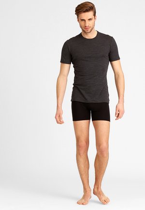 Dunkelgraues T-Shirt mit kurzen Ärmeln und schwarze Boxershorts an einem Modell, schlanker Schnitt, mit glatter Textur und einfachem Design, barfuß.
