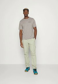 Grå melert kortermet t-skjorte, lysegrønne bukser og blåe treningssko med svarte og gule detaljer. Enkel design og avslappet passform.