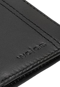 Černá kožená peněženka s viditelným prošitím, ražebním logem "wojas" a hladkou texturou. Kompaktní design zdůrazňující odolnost a řemeslné zpracování.