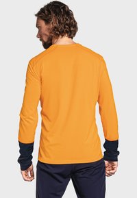 Långärmad skjorta i klar orange med marinblå mudd. Tillverkad av lättviktsmaterial, med rundhals och mjuk yta.