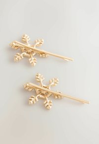 Guldtonade hårnålar formade som snöflingor med en strukturerad yta och bladliknande detaljer. Har en slät metallstång för att fästa.
