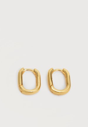 Pari pieniä, paksuja kultaisia ovaalinmuotoisia rengaskorvakoruja, joissa on sileä, kiillotettu pinta yksinkertaisella vaalealla taustalla.