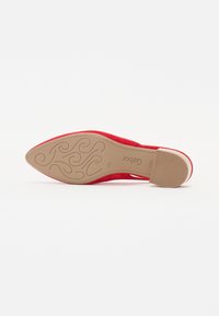 Scarpa con tacco alto in suede rosso, caratterizzata da una punta affusolata e una suola liscia in marrone chiaro con un motivo decorativo.