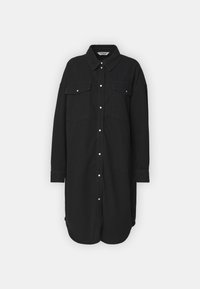 Musta nappikaulusliivi pitkillä hihoilla, kankaiset taskut ja kaareva helma. Sisältää klassisen kauluksen ja valkoiset nepparipainikkeet.