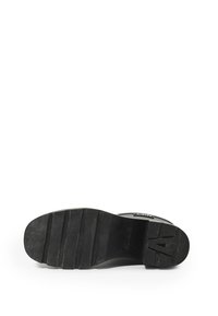 Black rubber sole with horizontal grooves, flat heel, and embossed letter "A." Minimalist design with no visible decorative elements.