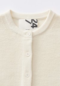 Knoop-down cardigan in crème, gemaakt van textuurgebreide stof, met een ronde halslijn en drie knopen aan de voorkant voor sluiting.