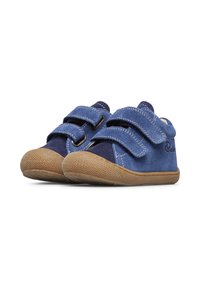 Zapatos infantiles de ante azul con dos correas de velcro, puntera redondeada y suela de goma texturizada en color marrón. Costuras blancas acentúan el diseño.