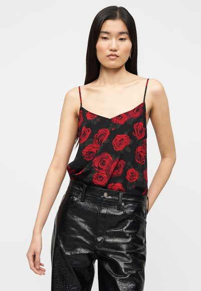 Μαύρο αμάνικο τοπ με κόκκινο τύπωμα τριαντάφυλλου, με V λαιμόκοψη και λεπτές τιράντες, συνδυασμένο με γυαλιστερό μαύρο παντελόνι από δερματίνη.