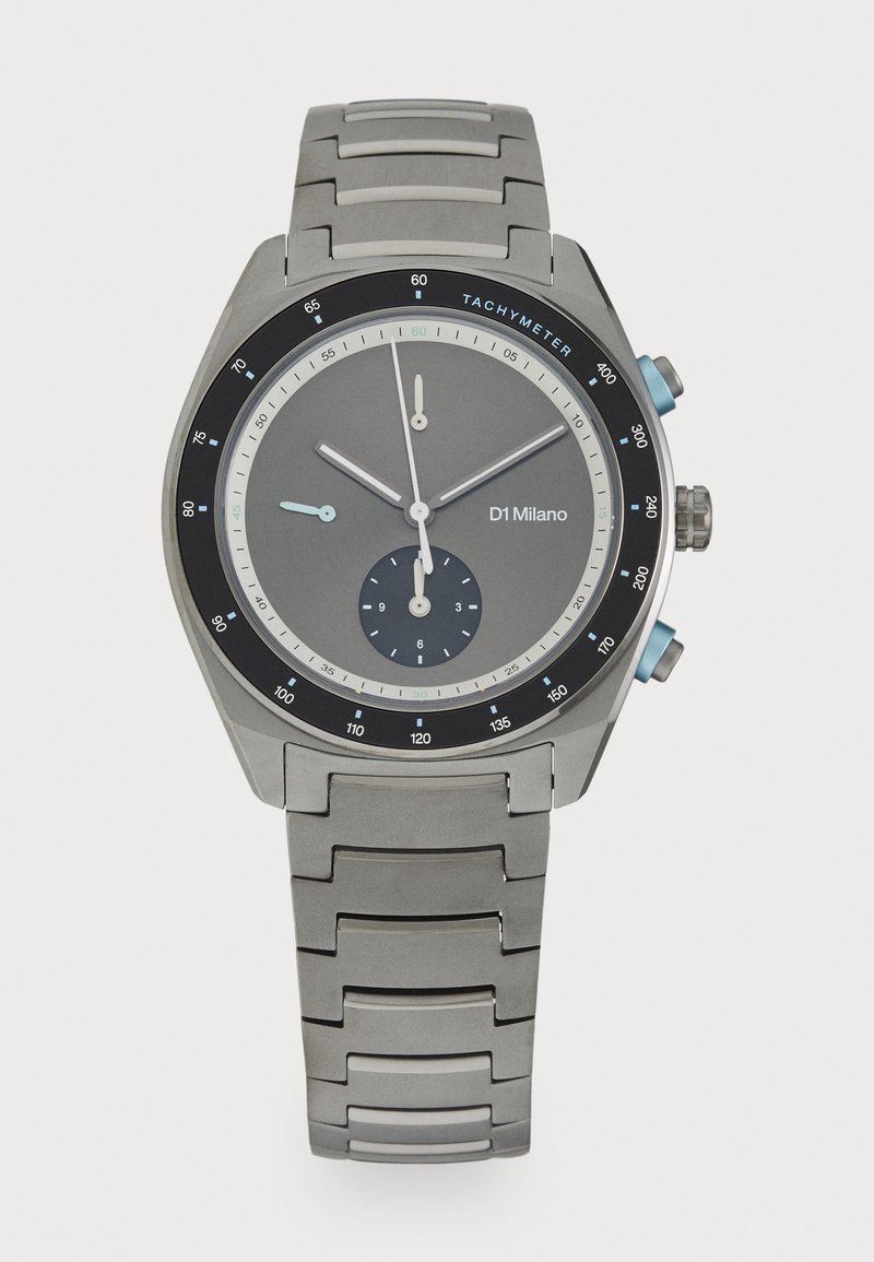 Sølv rustfrit stål ur med en rund grå urskive, sort tachymeter bezel, blå detaljer og et segmenteret armbåndsdesign.