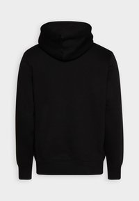 Svart hettegenser laget av mykt stoff, med stor hette, lange ermer og ribbestrikkede mansjetter. Baksiden er sømløs uten synlige grafikker.