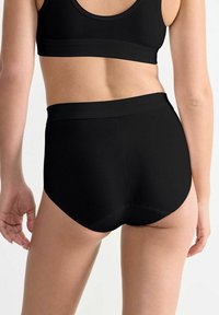 Schwarze Baumwollshorts mit hoher Taille, einem glatten Bund und nahtlosem Stoff, entworfen für Komfort und bedeckenden Sitz.