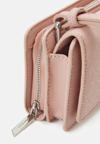 Lyserød syntetisk håndtaske med tekstureret overflade, flere rum, sølv lynlås og et præget logo-tag. Har et struktureret design.