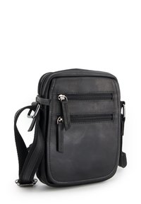 Černá kožená crossbody taška s dvěma předními zipovými kapsami, texturovaným povrchem a nastavitelným popruhem. Kompaktní obdélníkový design.