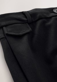 Black trousers with a smooth texture, featuring a side pocket, button closure, and belt loops, angled for detailed view of fabric and design.