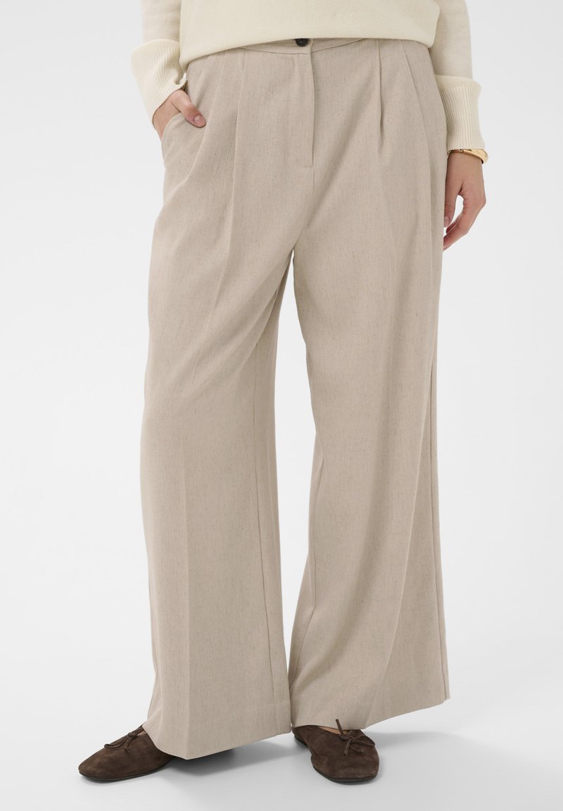 Beige laiad püksid sujuva tekstuuriga, esipleidiga, küljetaskute ja nööbiga vööl.