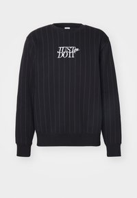 Fekete pulóver fehér függőleges csíkozással, kerek nyakkivágással és fehér „JUST DO IT” feliratú logóval. Puha anyag, bordázott mandzsetta és szegély.