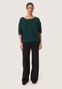 Teal, gestructureerde gebreide trui met korte mouwen, gecombineerd met zwart hooggetailleerde wijde broek met een ontspannen pasvorm en enkel-lange snit.