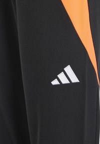 Schwarze Sporthose mit einem orangefarbenen diagonalen Streifen und einem weißen aufgestickten Adidas-Logo an der Seite, gefertigt aus einem eleganten, strapazierfähigen Stoff.