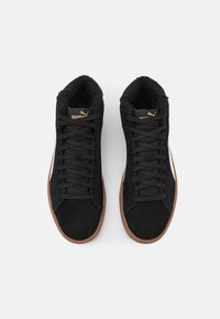 Černé vysoké tenisky s semišovým povrchem, gumovou podešví a polstrovaným límcem. Zlaté akcenty loga a ploché tkaničky dotvářejí design.