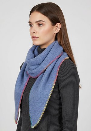Young woman with long brown hair wears a blue triangular scarf with colorful stitched edges over a black ribbed sweater, facing left.