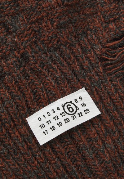 Tessuto lavorato a maglia in tonalità di rosso scuro e grigio, con un prominente motivo a spina di pesce e un'etichetta di cura che mostra la taglia 6 e i tag numerici.