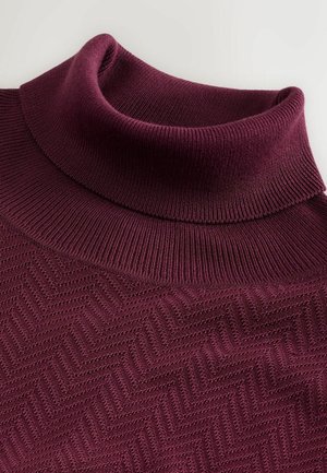 Burgundy polokrage tröja med ribbad textur och en chevronmönster. Mjuk stickad material med en hög, vikt krage.