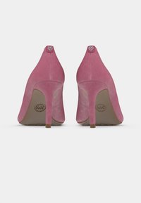 Vaaleanpunaiset mokkaiset korkeakorkoiset kengät, joissa on terävä kärki ja hoikka piikkikorko. Takana on pyöreä logokoriste. Sileä pinta.