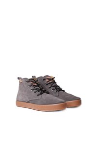 Botines de ante gris con cordones negros, suelas de goma marrón y acentos decorativos en la lengüeta. Presenta una superficie texturizada.