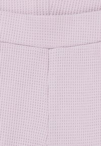 Licht lavendel kleurige wafelkatoen stof met gestructureerde horizontale ribbels; voorzien van een elastische tailleband en twee verticale naden voor extra vorm.