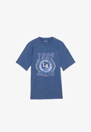 T-shirt graphique bleu, en coton, coupe relaxée. Présente une impression "1992" et "LA WORLD TOUR" avec des accents de laurier. Manches courtes et col rond.