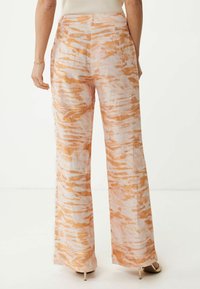 Pantalon à jambes larges en tissu léger, présentant un motif abstrait rose et orange avec une texture lisse et une taille haute.