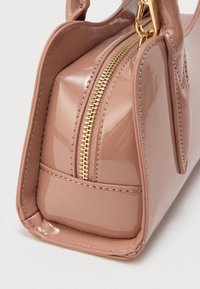 Sac à main rose brillant de forme rectangulaire, équipé d'une fermeture éclair dorée, d'accents texturés et de deux poignées courtes.