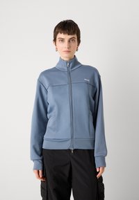 Light blue zip-up sweatshirt, high collar, ribbed cuffs, and side pockets; features BOSS logo on the chest and a smooth, textured fabric.
