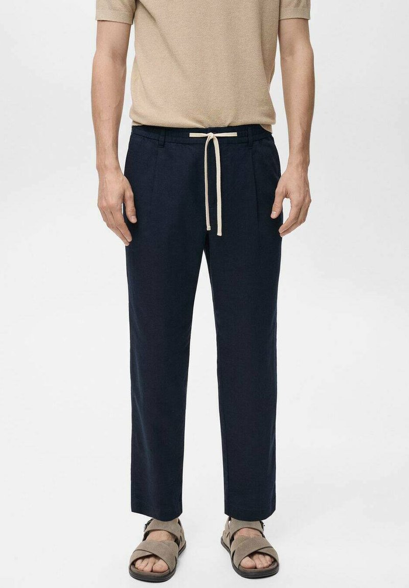 Marineblauwe broek met een ruime pasvorm, voorzien van een beige trekkoord in de taille. De stof oogt lichtgewicht en heeft een gladde textuur.