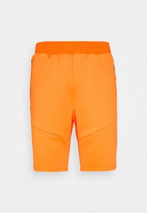 Lyse orange knælange shorts med elastik i taljen og subtile syninger på en ensartet lys baggrund.