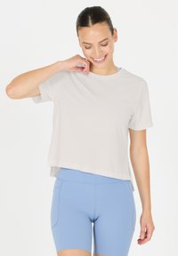 Ljust grå kortärmad skjorta med en avslappnad passform, med rak fåll och sidslitsar, ihop med mjuka blå träningsshorts.