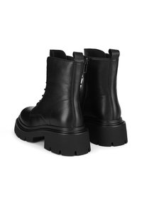 Czarne skórzane botki za kostkę na masywnej podeszwie, o gładkiej fakturze, z bocznymi zamkami i wyraźnymi detalami przeszyć.