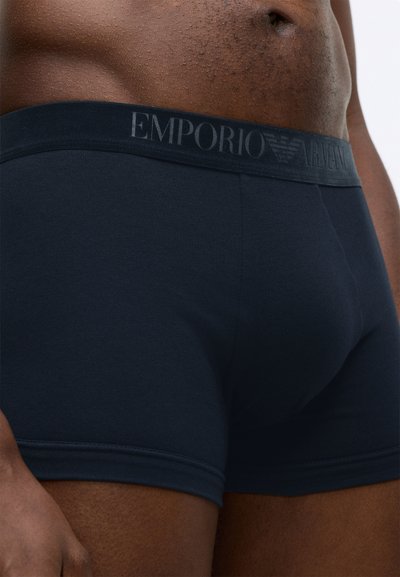 Tamnoplave pamučne bokserice s mekim elastičnim pojasom s logom "EMPORIO ARMANI". Glatka tekstura, prilagođeni dizajn i srednje dugi nogavice.
